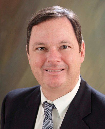 A man in a suit and tie smiles for the camera